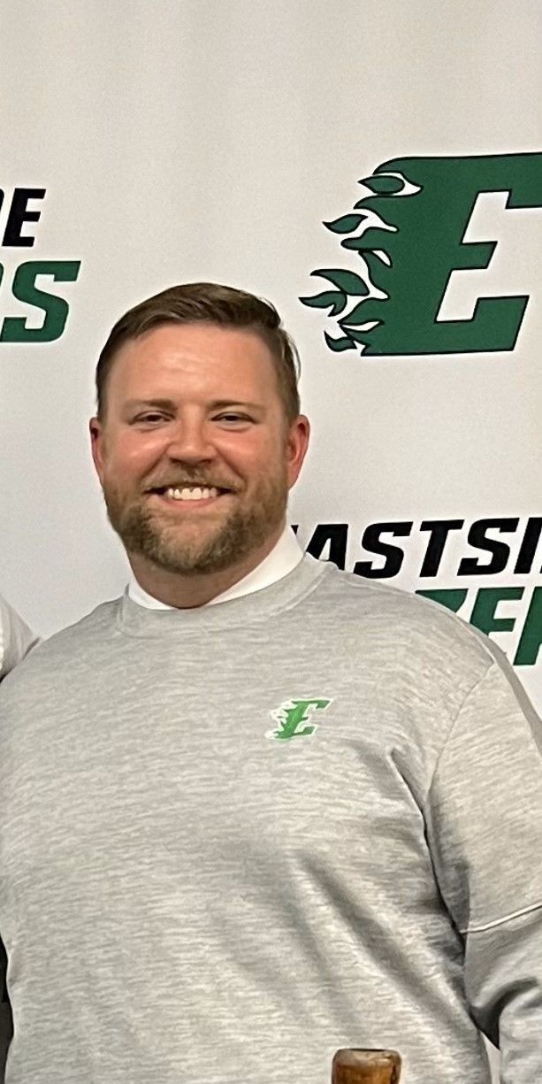 Individual wearing a gray Eastside Athletics sweatshirt standing against a backdrop with the Eastside logo.