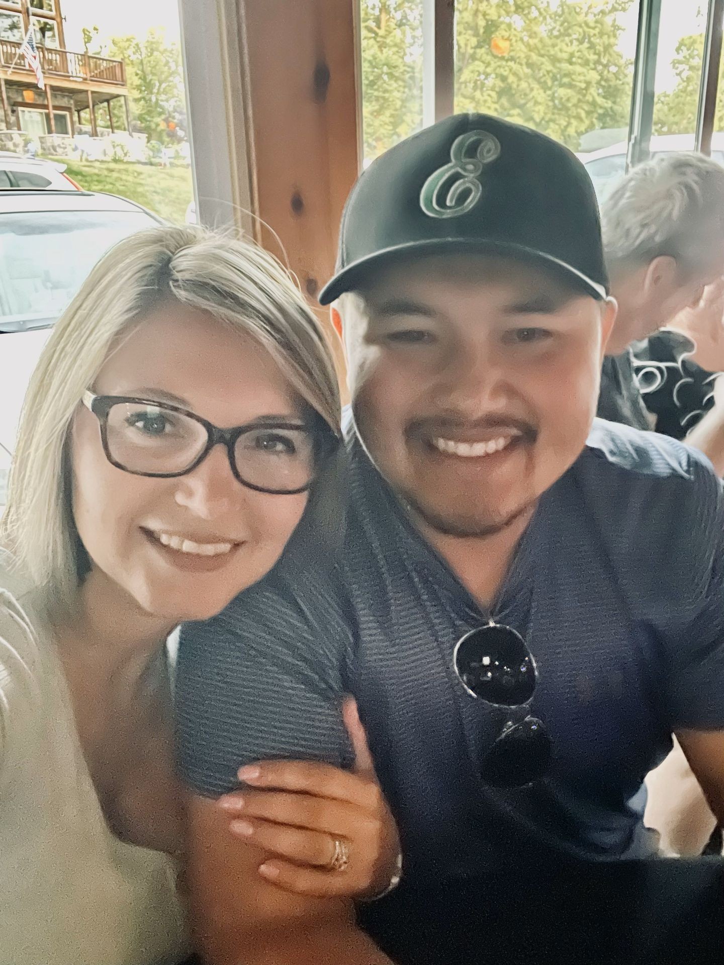 Smiling couple taking a selfie indoors with a window and greenery in the background.